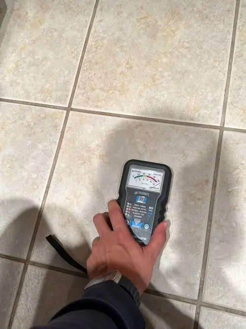 moisture meter readings indicate elevated moisture levels beneath the tile